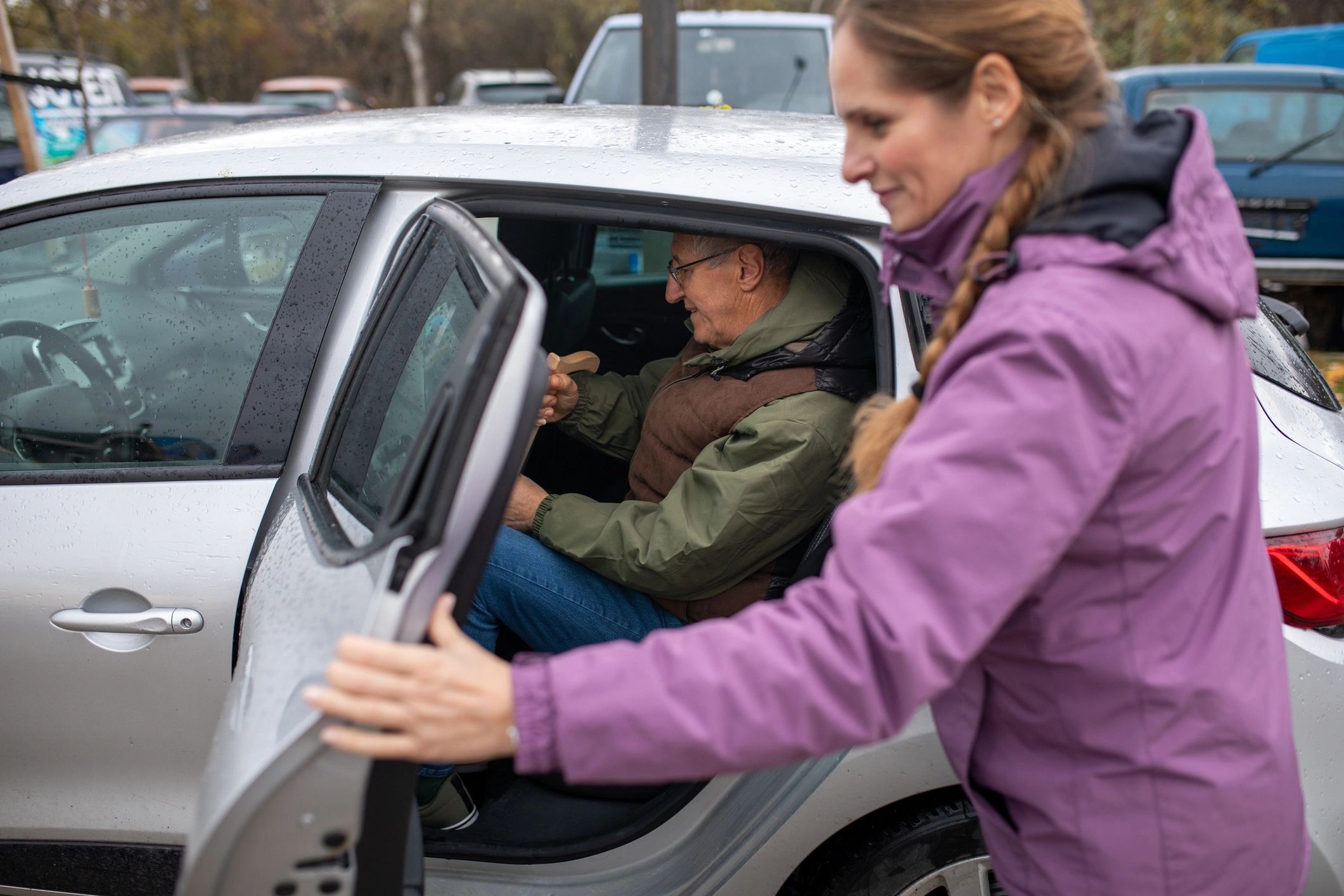 Driver assisting a passenger into a car